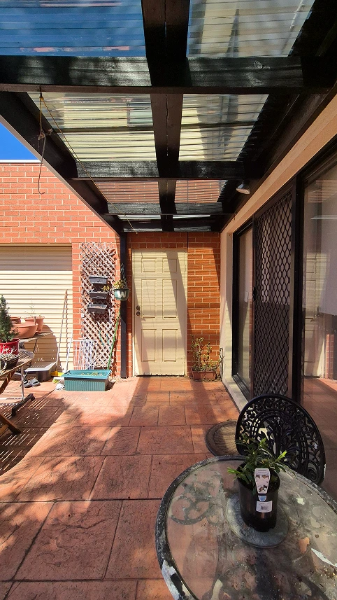Renovated back porch pergola at Aberfeldie with black beams, new clear roofing, and organized outdoor space