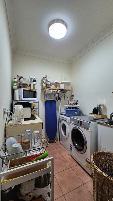 Kitchenette and laundry area before renovation in Aberfeldie with appliances and terracotta flooring