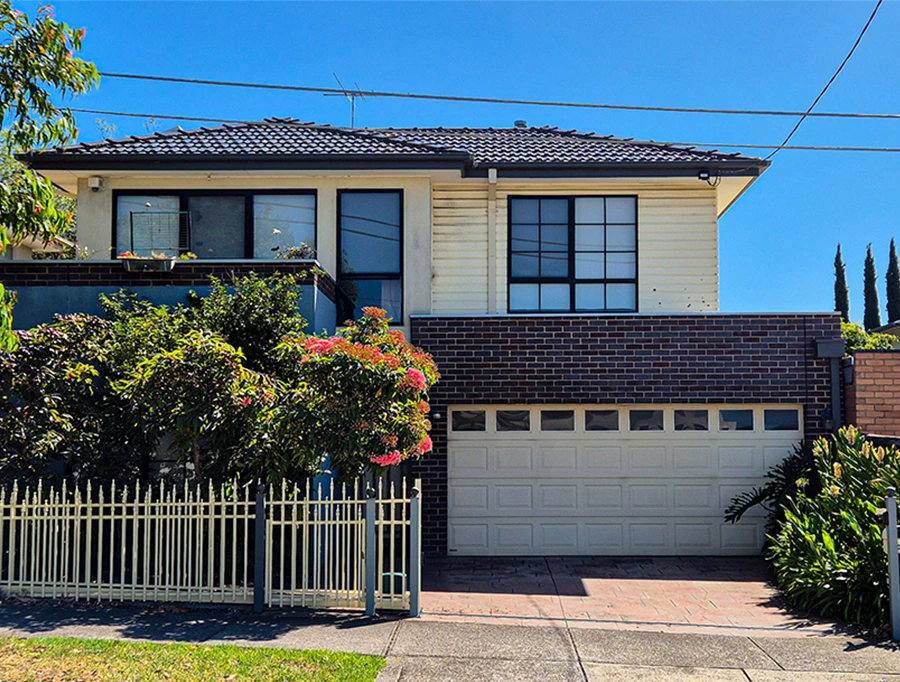 Contemporary two-story Aberfeldie home featuring brick and cream facade, manicured garden, and white picket fence.