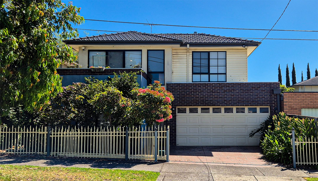 Charming two-story Aberfeldie family home featuring brick and cream facade, black tiled roof, landscaped garden and secure fencing on a sunny day