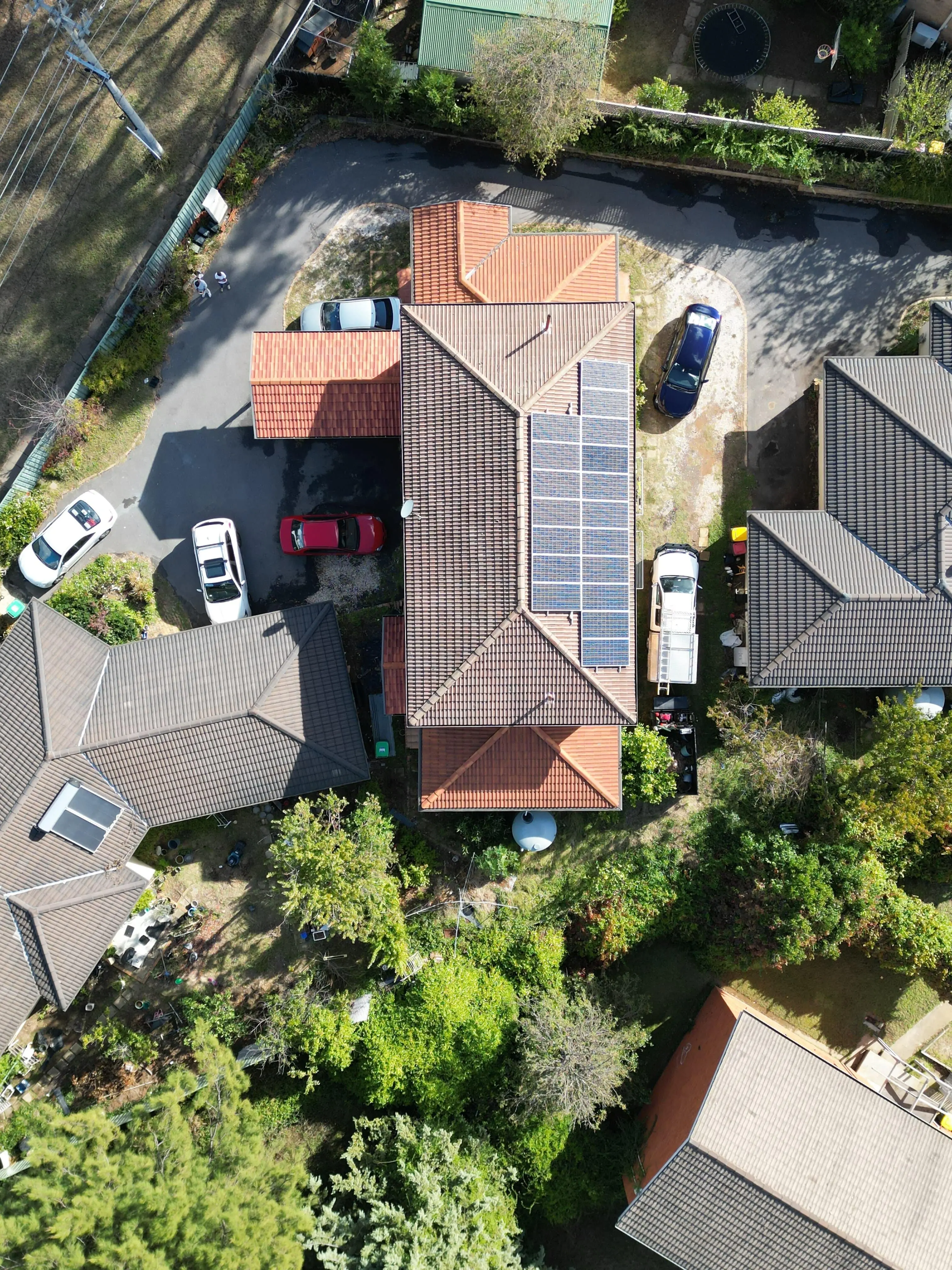 Aerial view of neighboring houses with mixed roof styles and solar panels