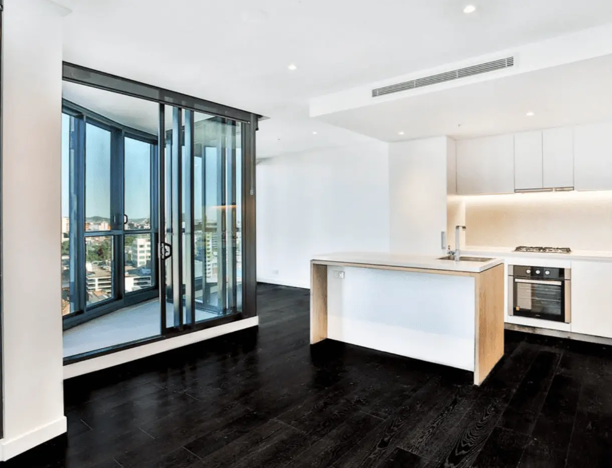 Modern white kitchen with dark floors and city views