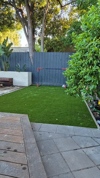 Final view of transformed Camberwell backyard showing artificial turf, paved borders, soccer goal and integrated gardens.