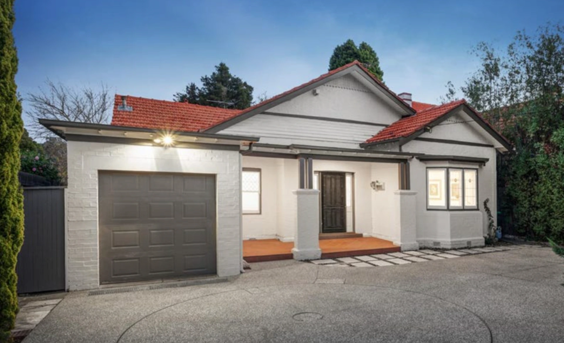 Charming two-story Aberfeldie family home featuring brick and cream facade, black tiled roof, landscaped garden and secure fencing on a sunny day