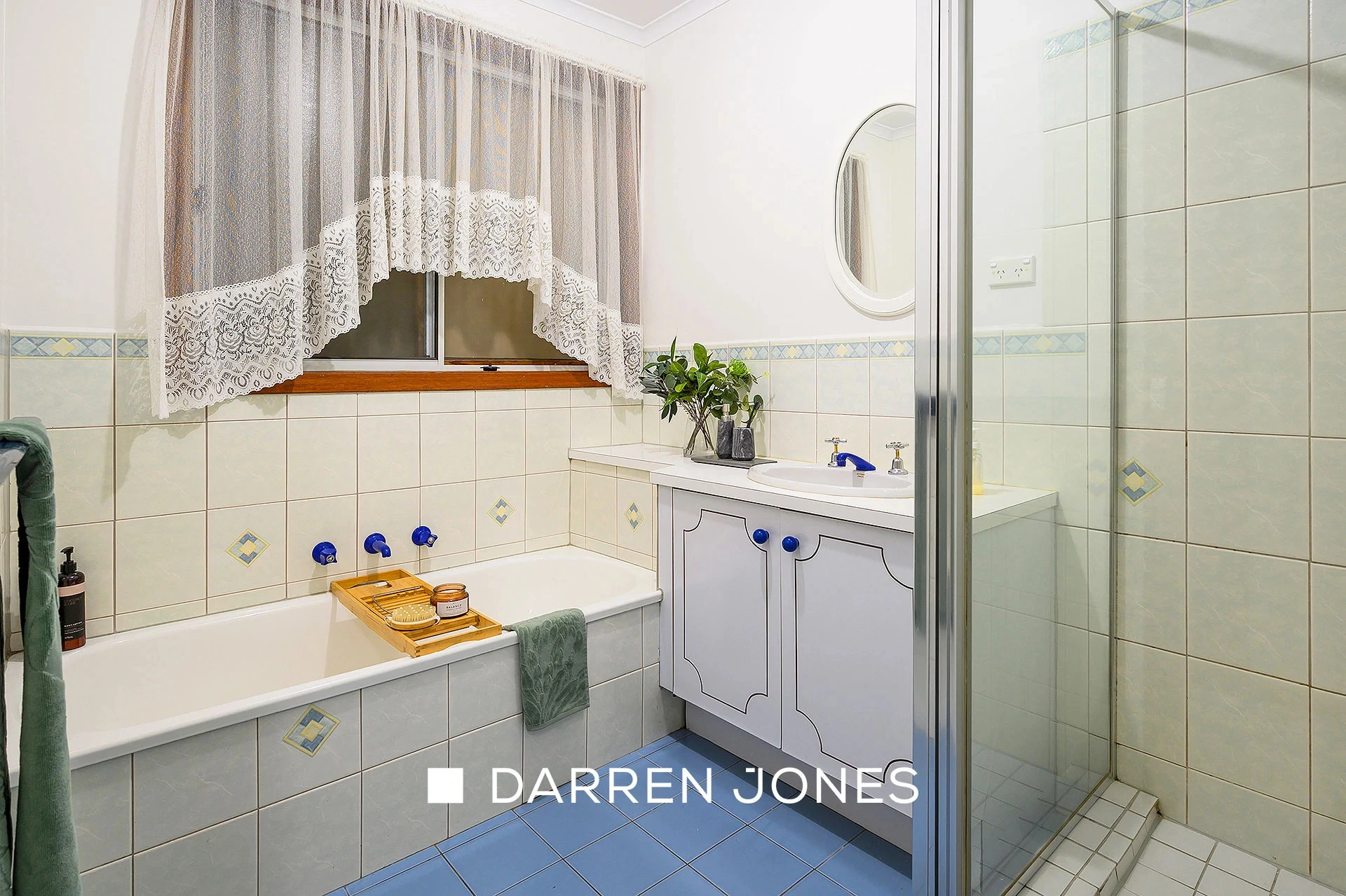 White tiled bathroom with bathtub and blue accent handles