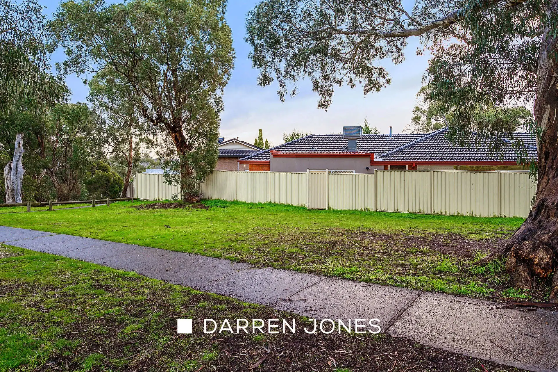 Large grassed area with mature gum trees and concrete path