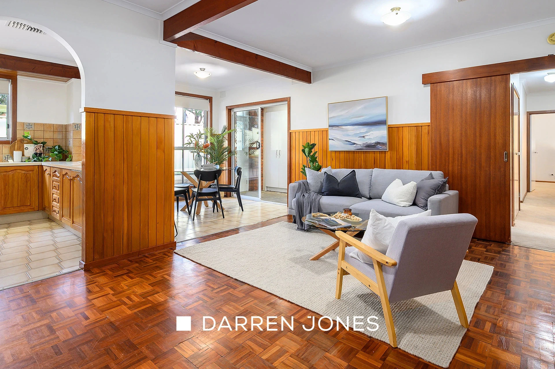 Living room with timber paneling, parquet floors and grey sofa
