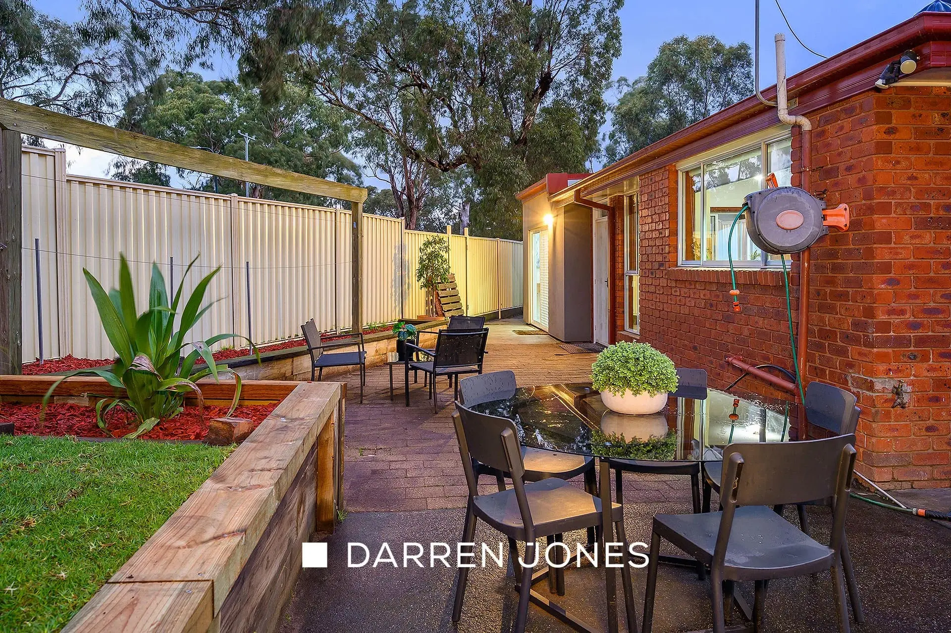 Timber deck with glass dining table and garden lighting