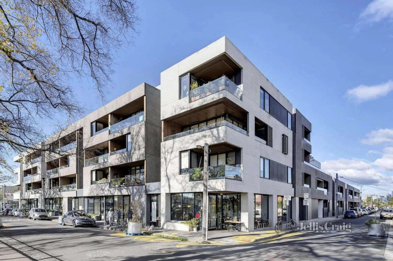 Modern four-story apartment building with retail spaces and balconies
