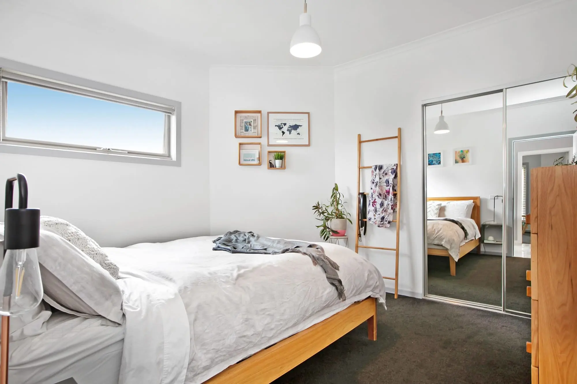 Modern bedroom with wooden bed frame and mirrored wardrobes