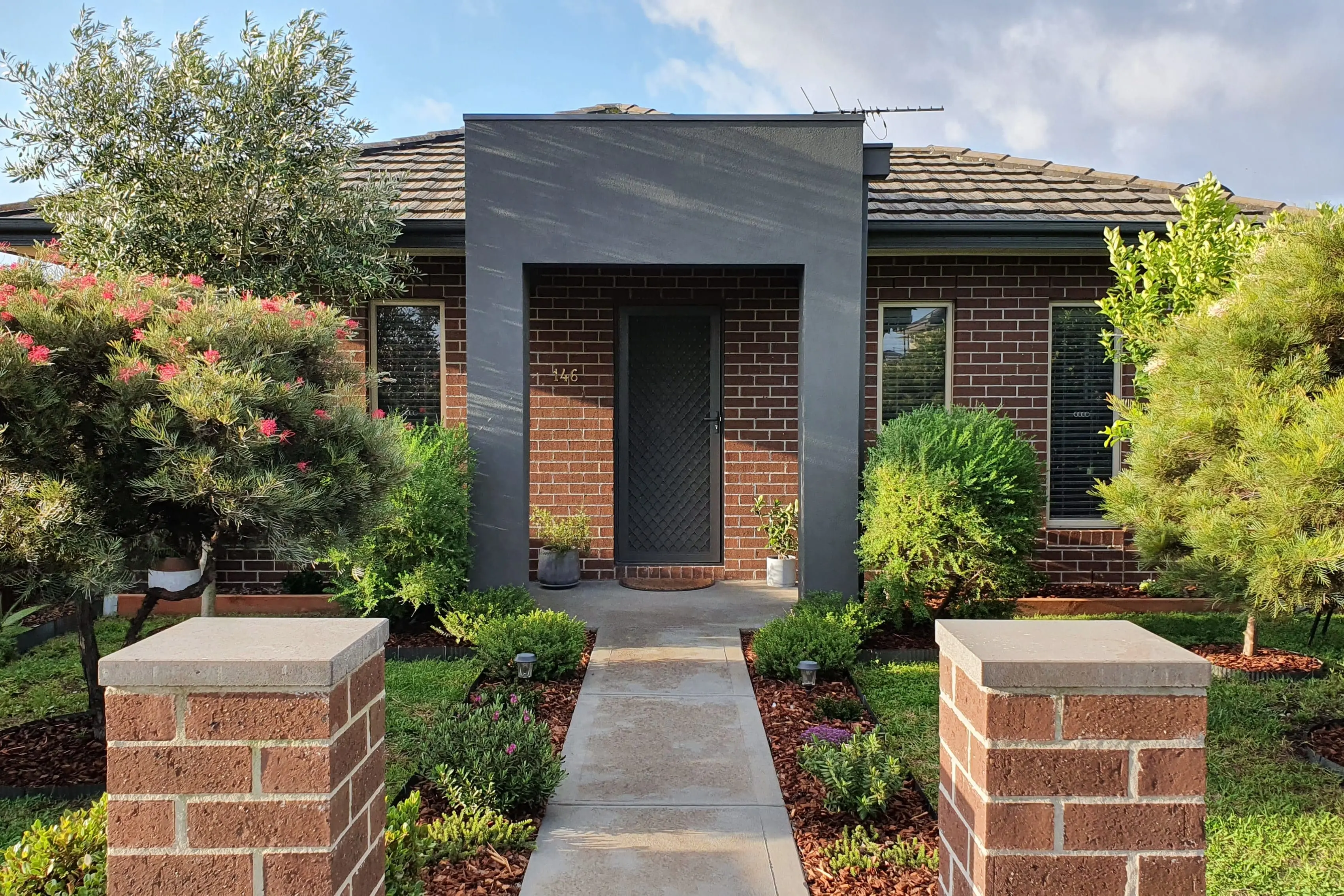 Modern brick house entrance with symmetrical native garden beds