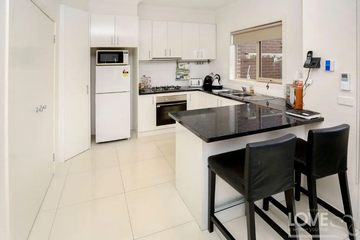 White modern kitchen with black benchtops and breakfast bar