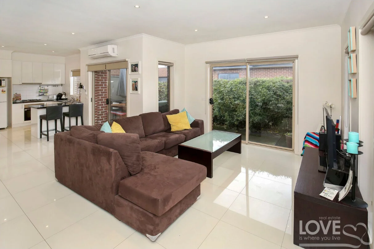 Modern open plan living room with brown sofa and white tiles