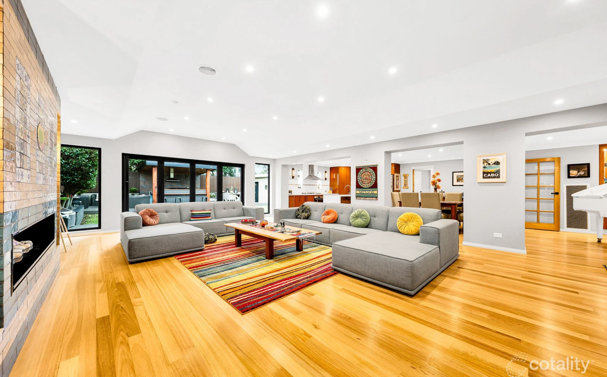 Spacious modern living room in Mill Park home with timber floors, grey sofas, and colorful décor