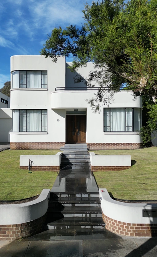 Modern art deco style white house with curved architecture, large windows, and newly laid turf landscaping featuring a sleek walkway and minimalist design