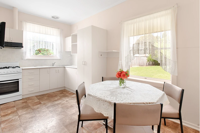 Kitchen and dining area before renovation in Mt. Gambier with white cabinets, gas stove, and round dining table
