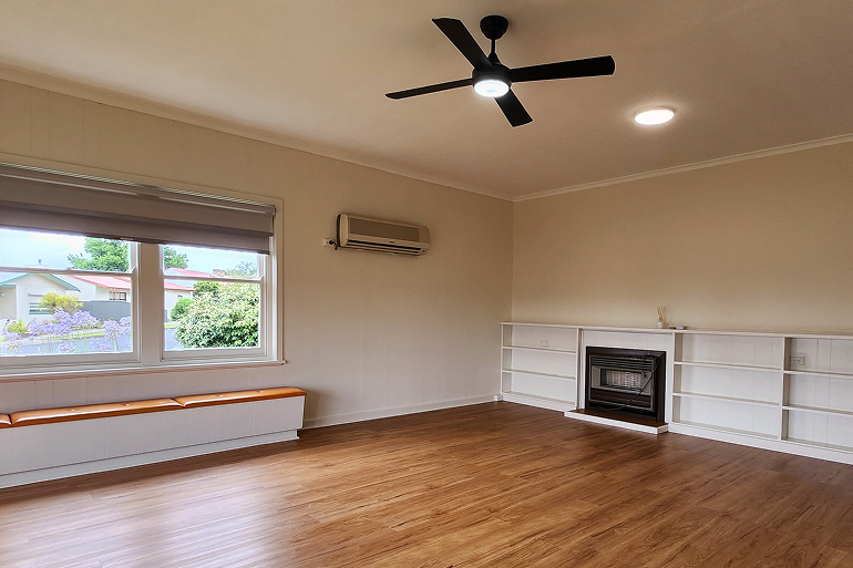 Renovated living room in Mt. Gambier featuring wooden floors, built-in shelving, modern fan, and window bench seating