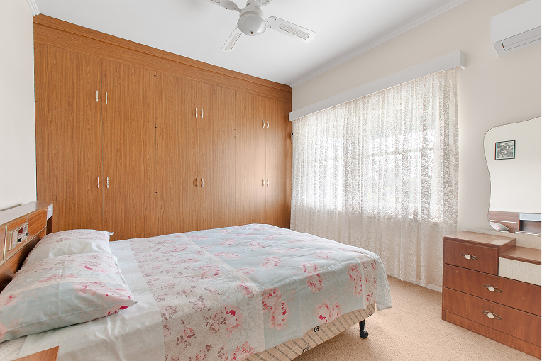 Master bedroom before renovation in Mt. Gambier property with wooden wardrobe and floral bedspread