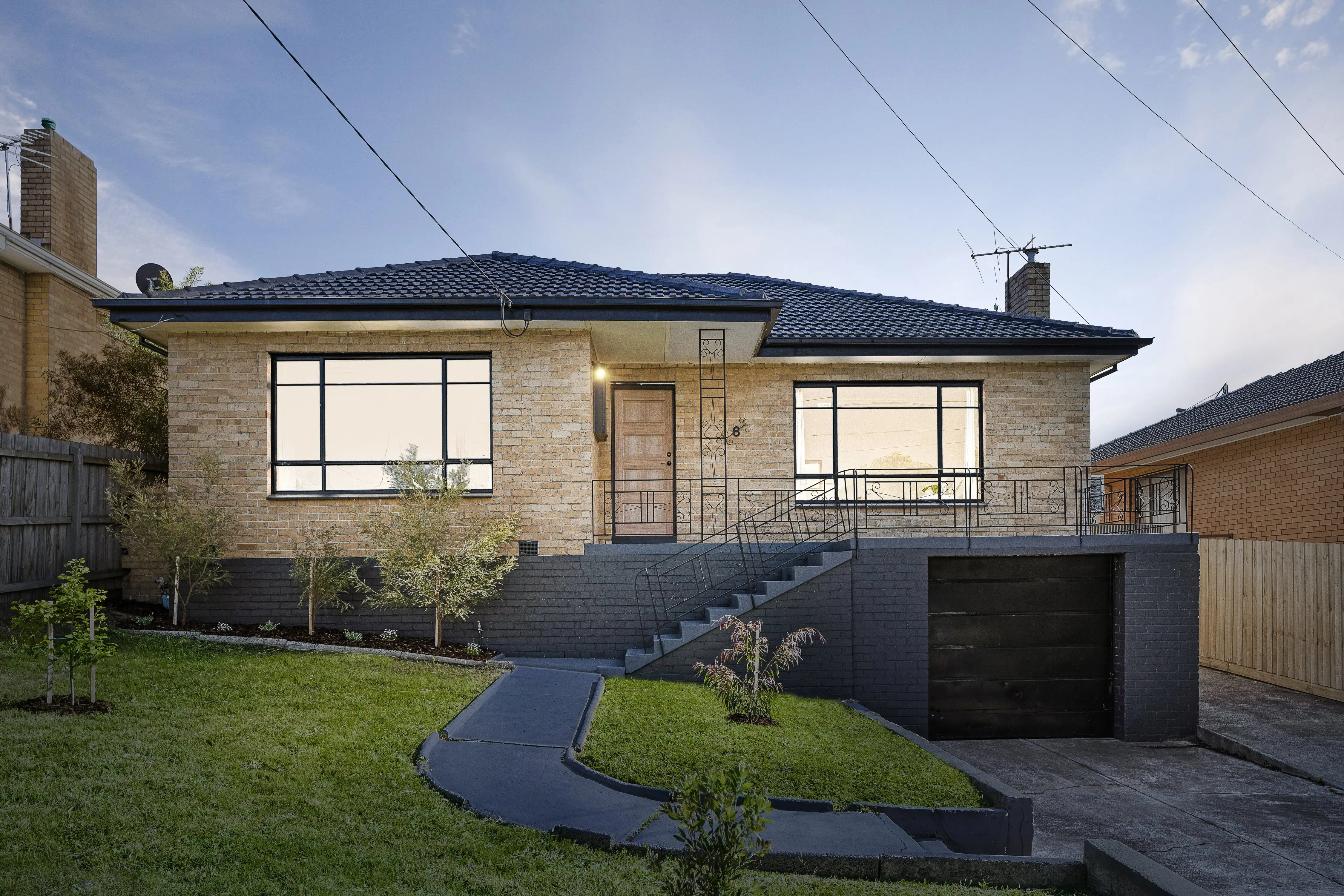Renovated cream brick house with navy roof and dark grey base at twilight