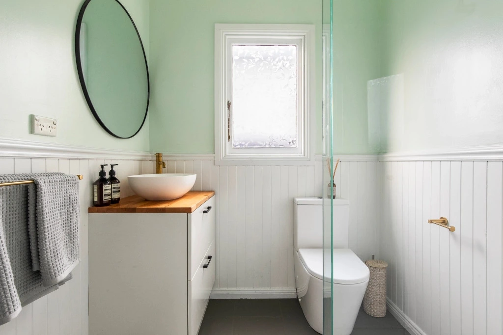 Modern bathroom with mint walls and wooden vanity
