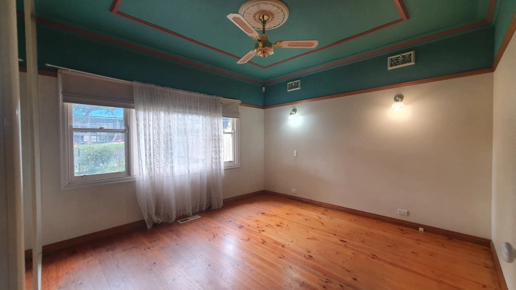 Empty bedroom with teal ceiling and timber flooring