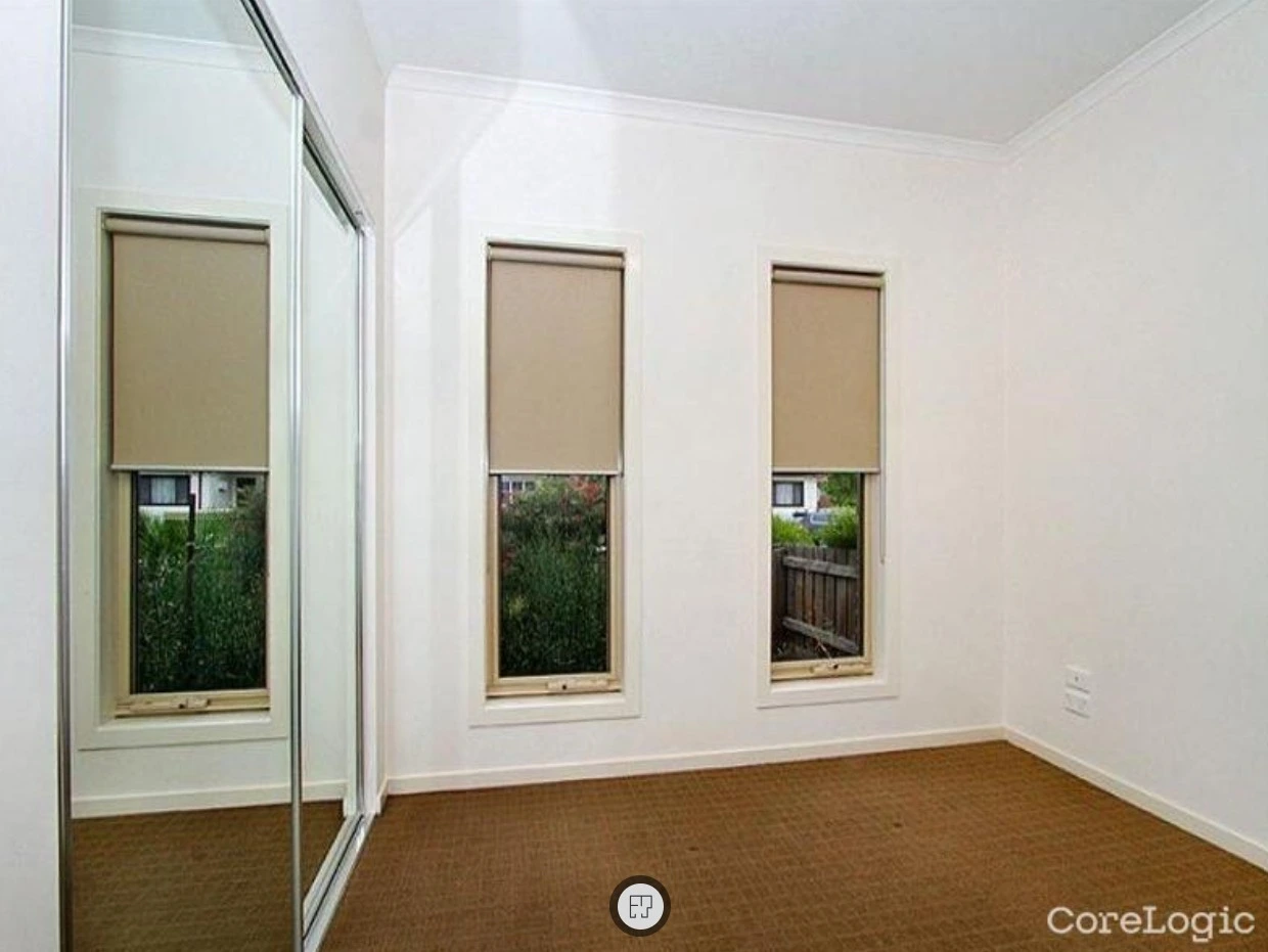 Bedroom with mirrored wardrobe and three windows in Reservoir property before renovation updates