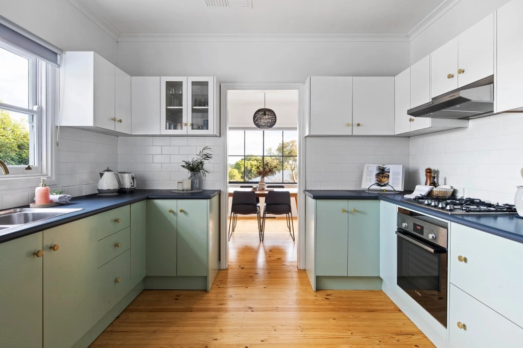 Modern two-tone kitchen with sage cabinets and brass hardware