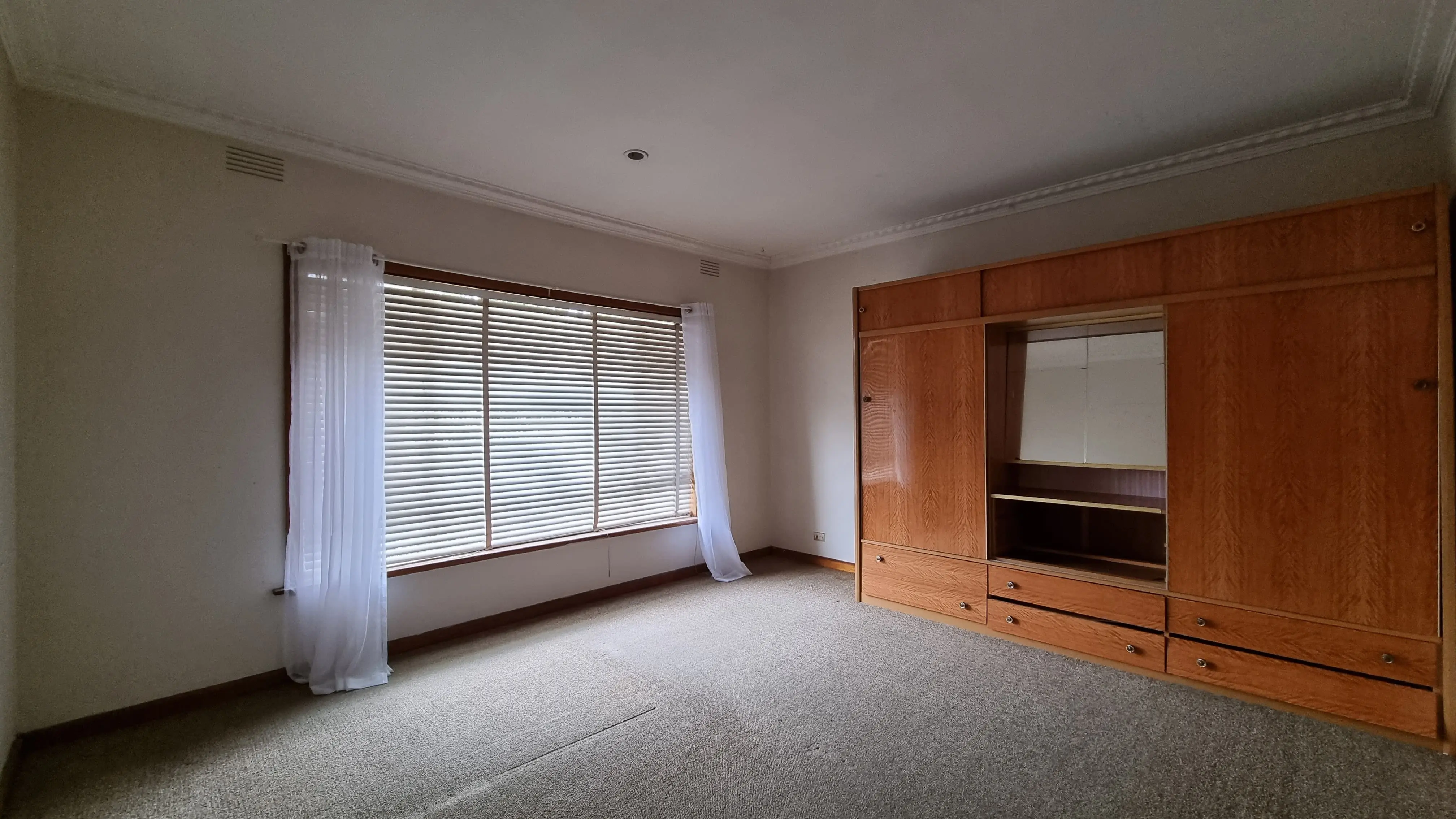 Empty bedroom with timber wardrobe and grey carpet