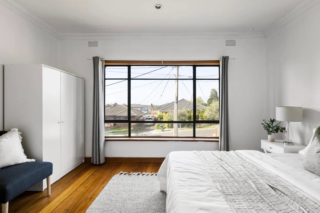 Modern bedroom with timber floors and black window frames