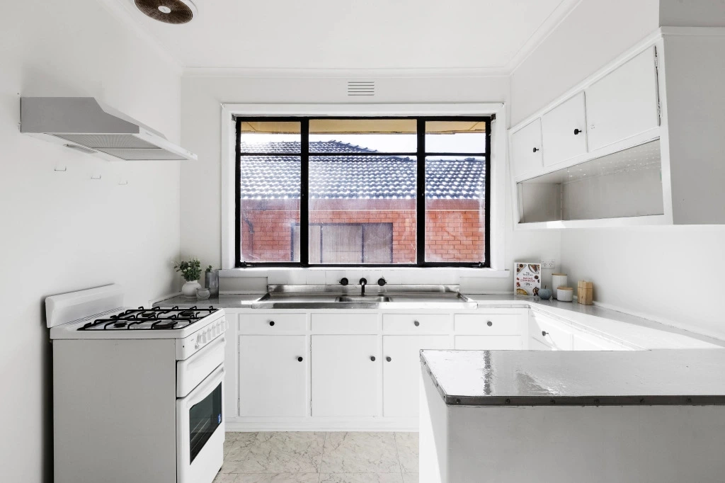 Modern white kitchen with black window frames and stone benchtops