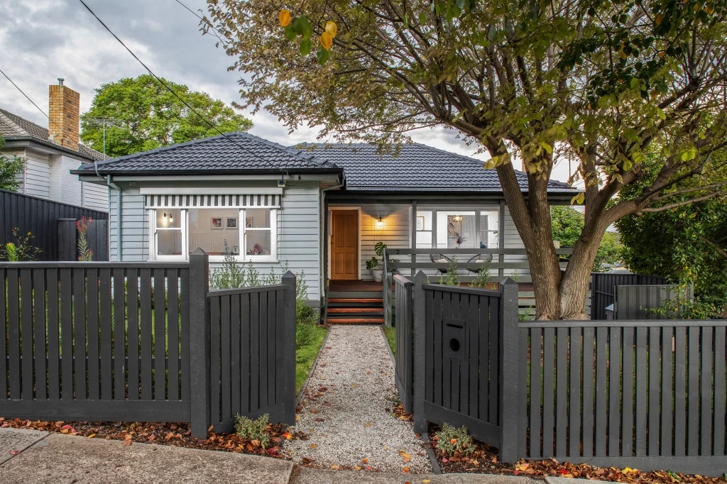 Modern renovated weatherboard house with grey fence in Melbourne