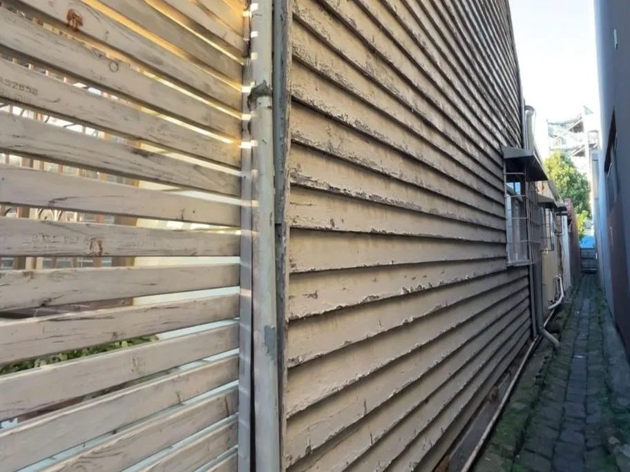 Weathered weatherboard exterior with peeling paint requiring restoration