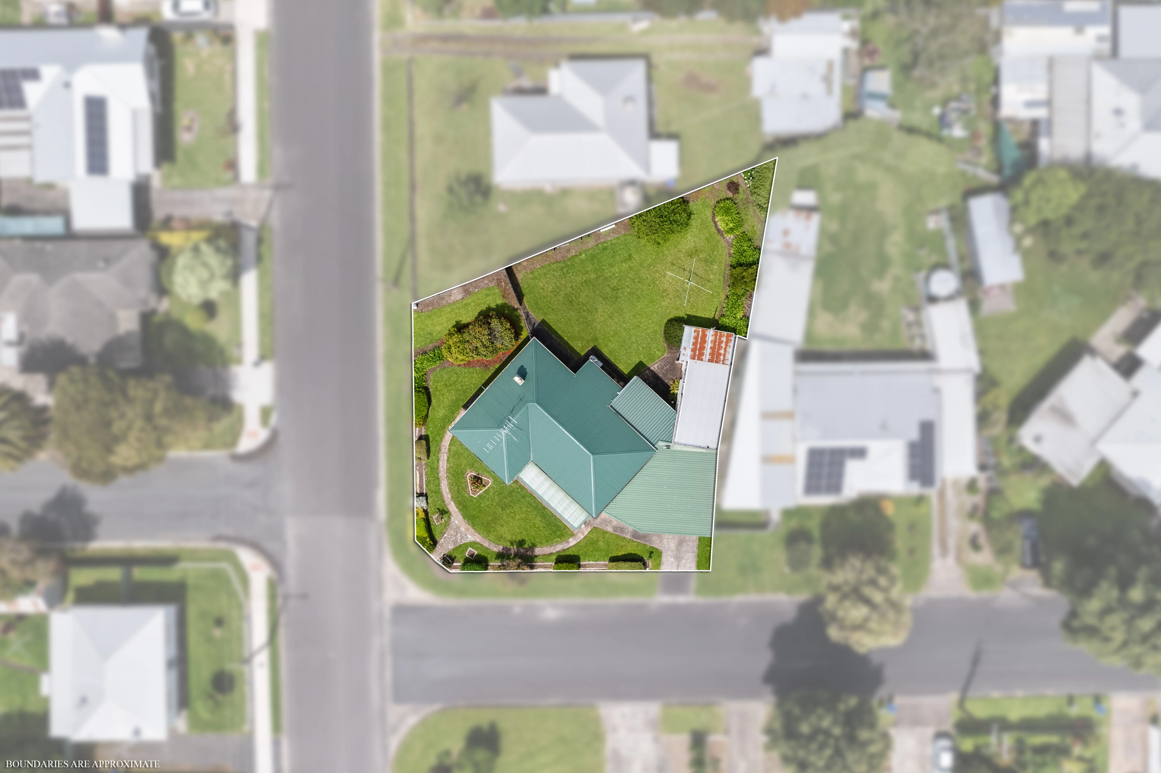 Aerial view of corner house with green roof and landscaped yard