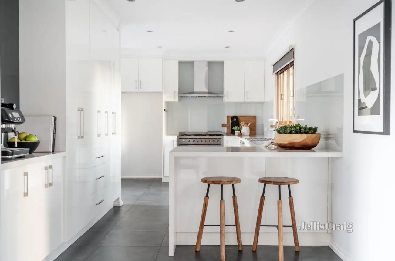 White modern kitchen with peninsula and wooden stools